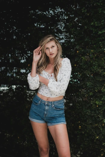 a woman posing for a picture in front of some trees, unsplash contest winner, renaissance, wearing denim short shorts, erin moriarty, exposed midriff, in front of white back drop