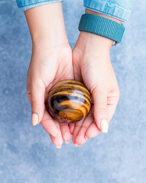 a person holding a wooden object in their hands, by Julia Pishtar, unsplash, hurufiyya, holding a rainbow tiger gem, ferrofluid, blue marble, high resolution product photo