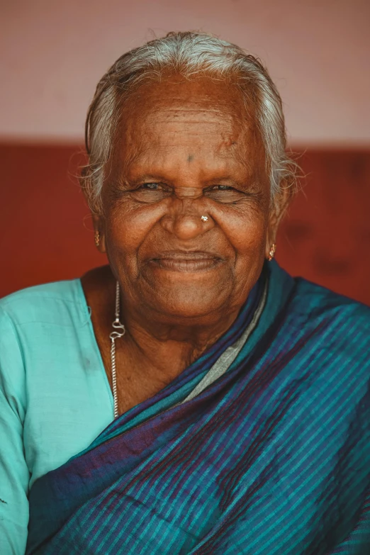 a woman in a blue and green sari, an album cover, pexels contest winner, the look of an elderly person, brown smiling eyes, sri lanka, taken in the late 2010s