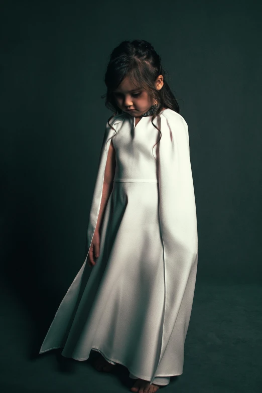 a little girl in a white dress and cape, inspired by Thomas Lawrence, unsplash, conceptual art, dark. studio lighting, sleek robes, epk, frown fashion model