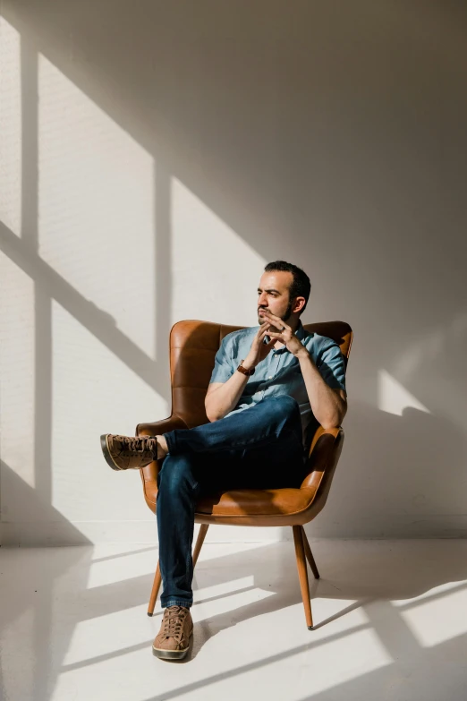 a man sitting in a chair in front of a window, a portrait, inspired by Germán Londoño, pexels contest winner, eng kilian, sitting on designer chair, genndy tartakovsky, profile pic