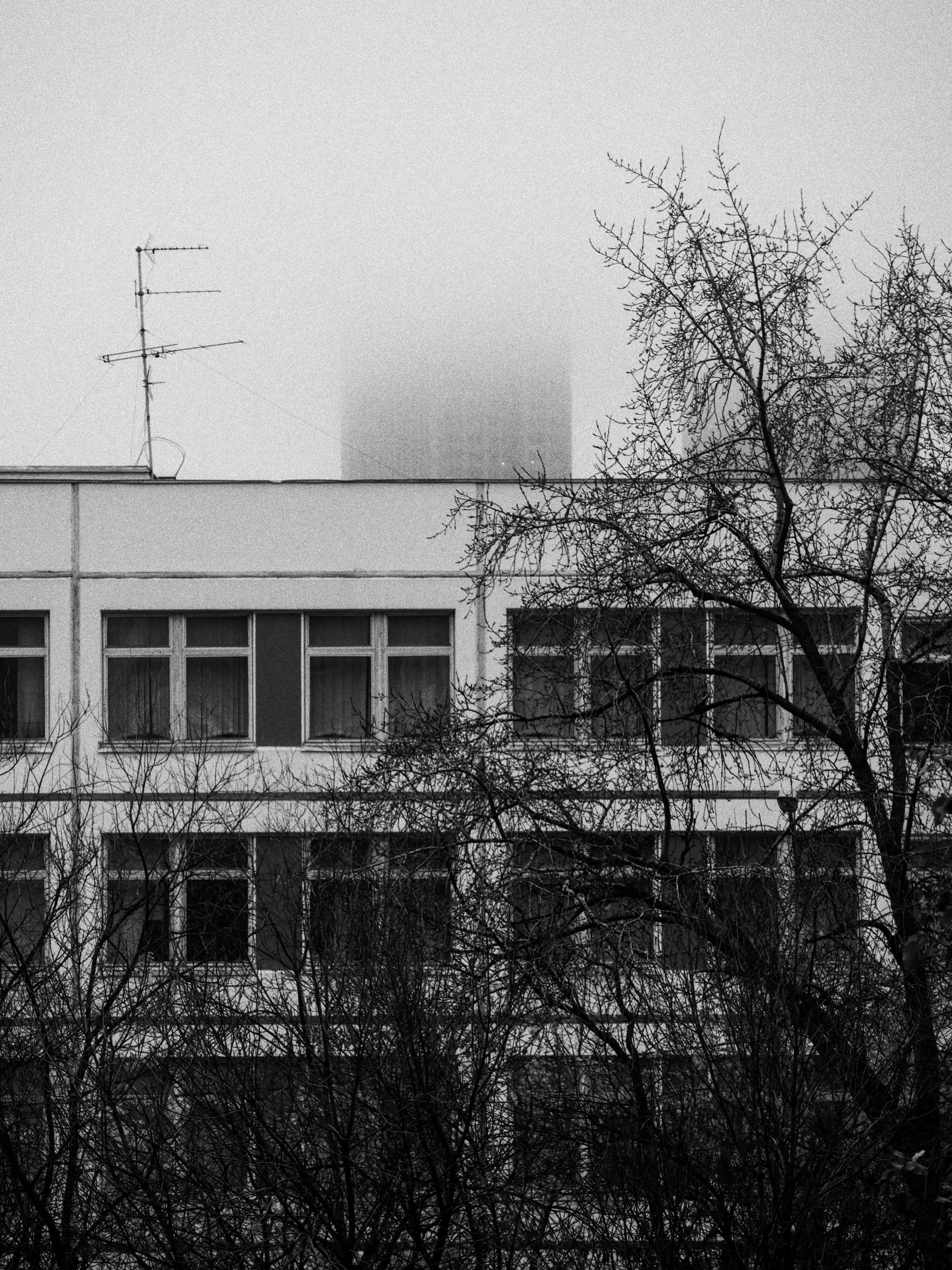 a black and white photo of a building in the fog, a black and white photo, by andrei riabovitchev, unsplash, brutalism, magical soviet town, hospital, fog!!!, neo kyiv