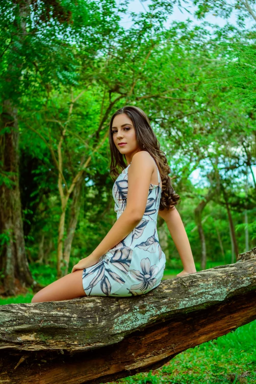 a woman sitting on a log in a forest, a portrait, by david rubín, art photography, elegant tropical prints, short dress, 18 years old, color photograph portrait 4k