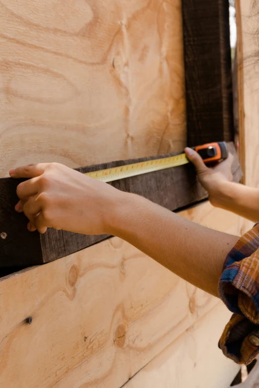 a person using a tape measure to measure a wall, inspired by Donald Judd, unsplash, renaissance, rustic wood, square, brown, van