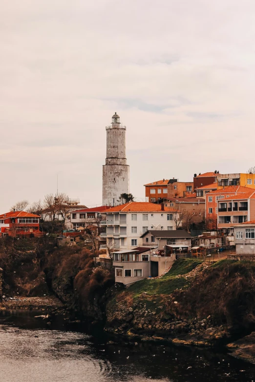 a number of buildings near a body of water, lighthouse, cliffside town, can basdogan, slide show