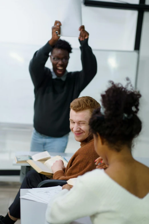 a group of people sitting around each other in a room, cheering, standing in class, struggling, diverse