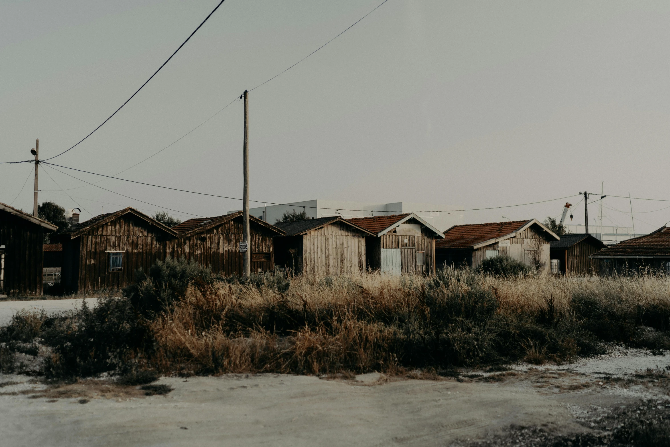 a couple of houses sitting on the side of a road, an album cover, unsplash, rural wastelands, background image, wooden structures, 2 0 0 0's photo