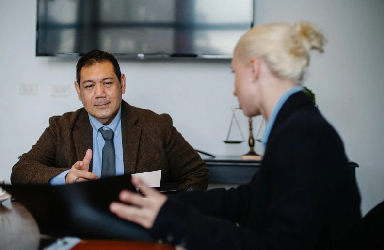 a man and a woman sitting at a table, lawyer clothing, darren quach, thumbnail, te pae