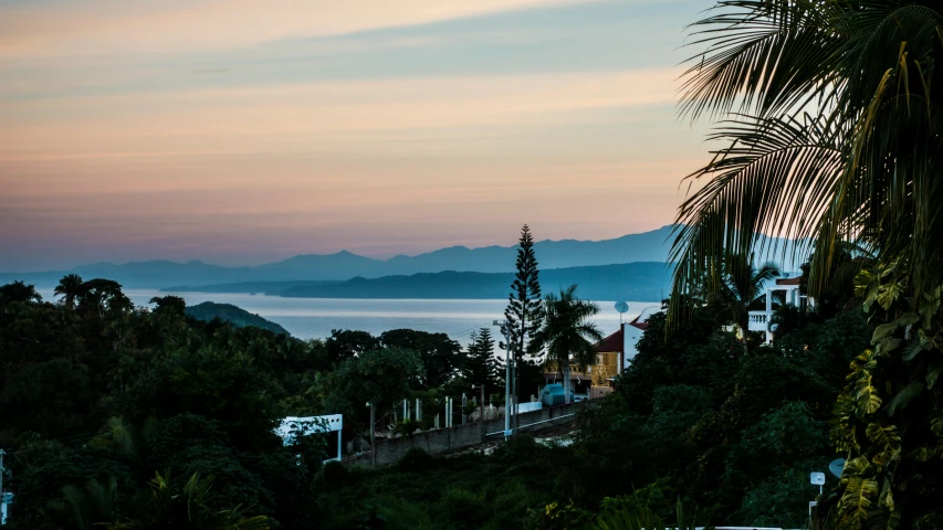 a view of the ocean from the top of a hill, by Daniel Lieske, unsplash contest winner, outdoors tropical cityscape, distant mountains lights photo, early morning light, tia masic