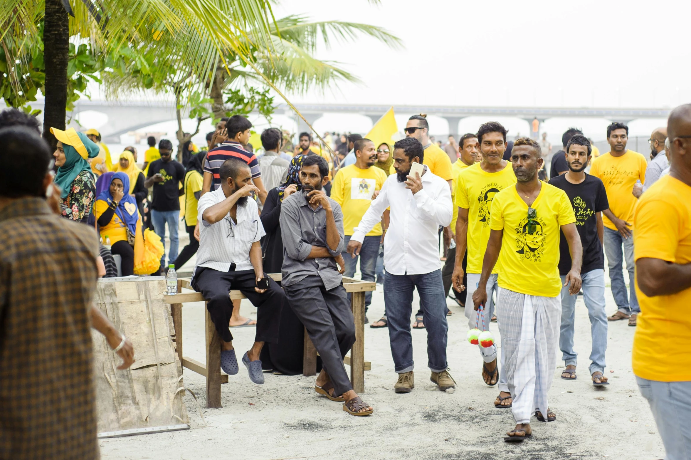 a group of men standing next to each other on a beach, unsplash, hurufiyya, yellow and black color scheme, malayalis attacking, protest, people outside walk