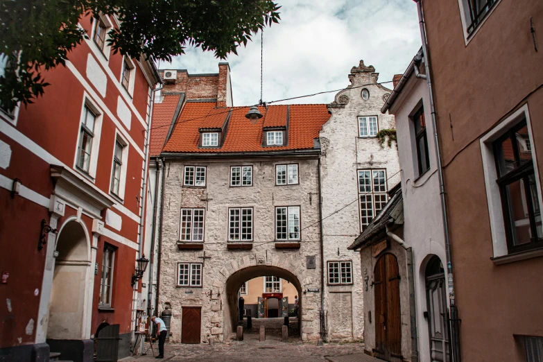 a couple of buildings that are next to each other, by Emma Andijewska, pexels contest winner, art nouveau, medieval gates, cobblestone, white buildings with red roofs, 1759