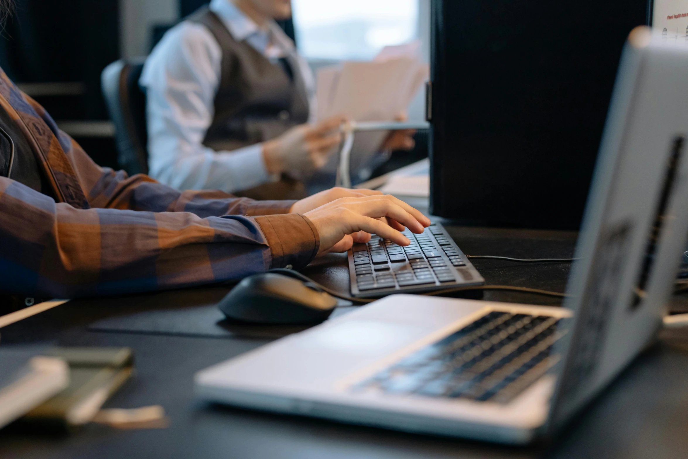 a man sitting at a desk using a laptop computer, trending on pexels, medium shot of two characters, bottom angle, high quality photo, lachlan bailey