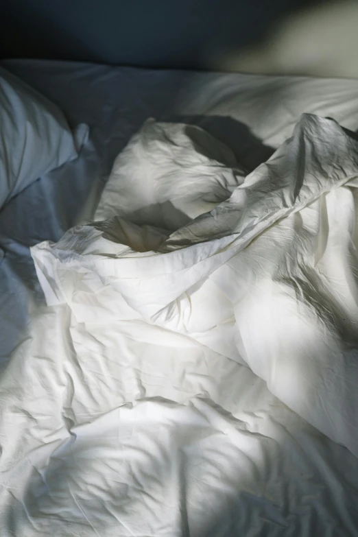 an unmade bed with white sheets and pillows, inspired by Elsa Bleda, unsplash, process art, decaying dappled sunlight, photographed for reuters, wrinkled, 2010s