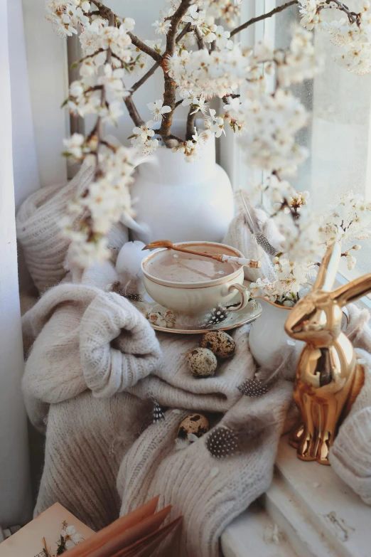 a white vase sitting on top of a window sill, a picture, by Zofia Stryjenska, trending on pexels, bunnies, hot cocoa drink, gold decorations, spring theme