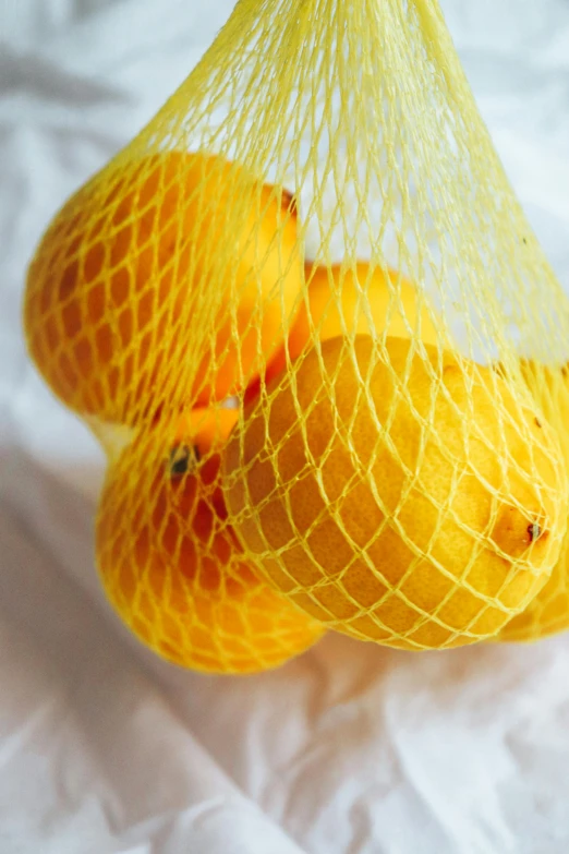 a bag of lemons sitting on top of a white sheet, net art, oranges, shopping groceries, zoomed in, webbing