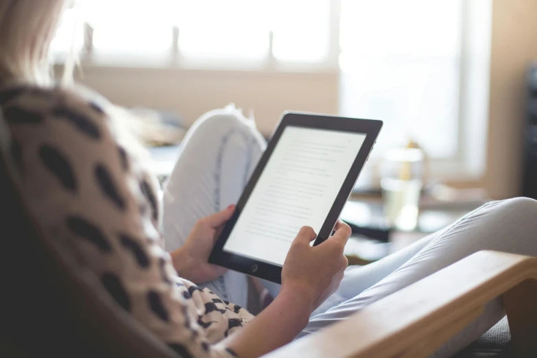 a woman sitting in a chair reading a book, pexels contest winner, holding glowing laptop computer, natural lighting, bottom angle, no - text no - logo