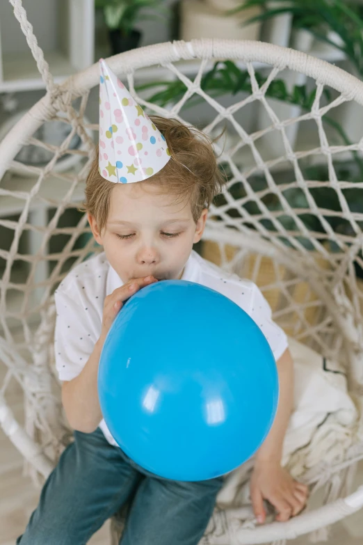 a little boy sitting in a swing chair with a blue balloon, pexels contest winner, happening, party hats, boy with neutral face, profile image, hand over mouth