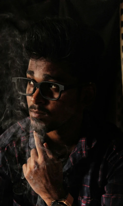 a man smoking a cigarette in a dark room, a character portrait, pexels contest winner, hurufiyya, with nerdy glasses and goatee, provocative indian, trending on artstion, sittin