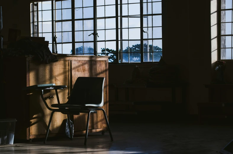 a chair that is sitting in front of a window, unsplash contest winner, light and space, stood in a factory, schools, late afternoon sun, classroom