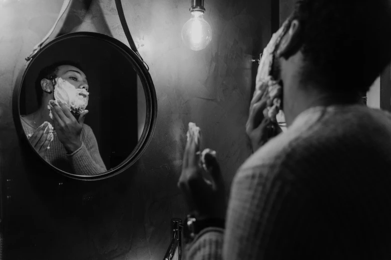 a man shaving his face in front of a mirror, a black and white photo, by Emma Andijewska, pexels contest winner, evening lighting, dark-skinned, round mirror on the wall, thumbnail