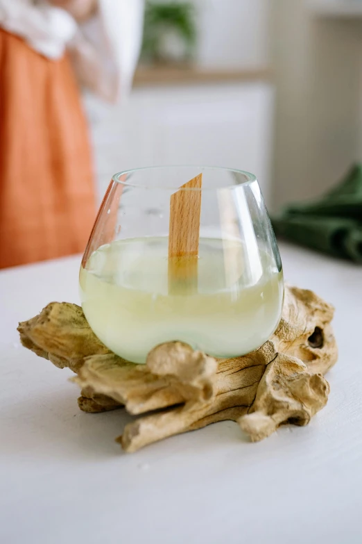 a glass filled with liquid sitting on top of a table, inspired by Géza Dósa, driftwood, bamboo wood, sleek white, island