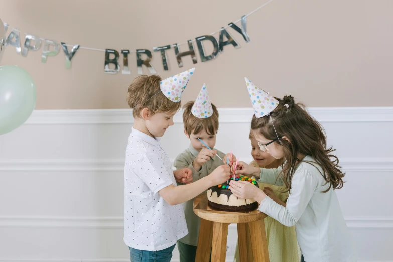 a group of children standing around a birthday cake, by Nicolette Macnamara, pexels, decoration around the room, grey, background image