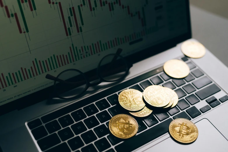 a laptop computer sitting on top of a desk covered in coins, by Julia Pishtar, trending on unsplash, hurufiyya, waveforms on top of square chart, bitcoin, wearing many medallions, 🚿🗝📝