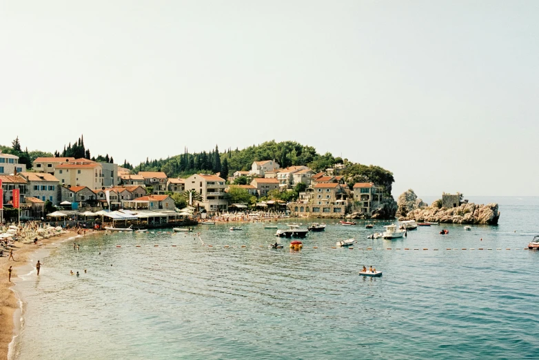 a group of people standing on top of a beach next to a body of water, renaissance, dubrovnik, in muted colours, boats in the water, conde nast traveler photo