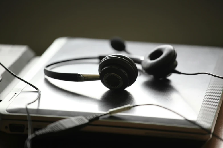 a pair of headphones sitting on top of a laptop, an album cover, pexels, realism, in an call centre office, afp, black wired cables, telephone