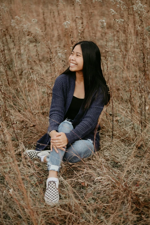 a woman sitting in a field of tall grass, inspired by Ruth Jên, pexels contest winner, in a navy blue sweater, satisfied pose, young asian girl, view(full body + zoomed out)