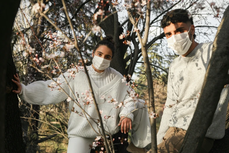 a man and a woman standing next to each other in a tree, trending on pexels, renaissance, wearing facemask, wearing a white sweater, spring fashion, promotional image