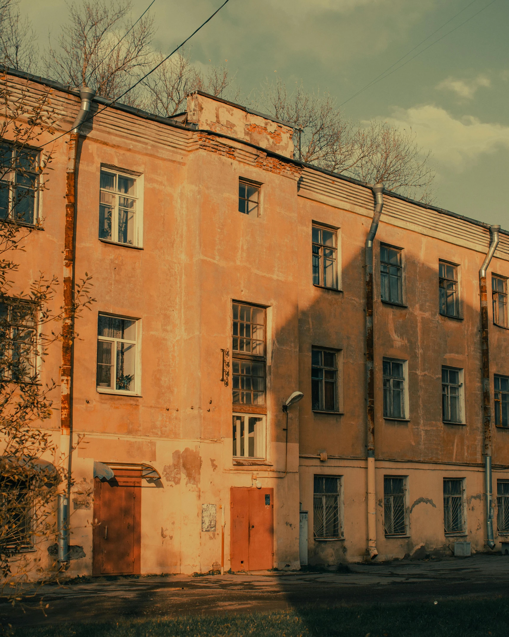 a red fire hydrant sitting on the side of a road, an album cover, inspired by Elsa Bleda, pexels contest winner, socialist realism, soviet apartment building, light - brown wall, an old abandoned mansion, (golden hour)