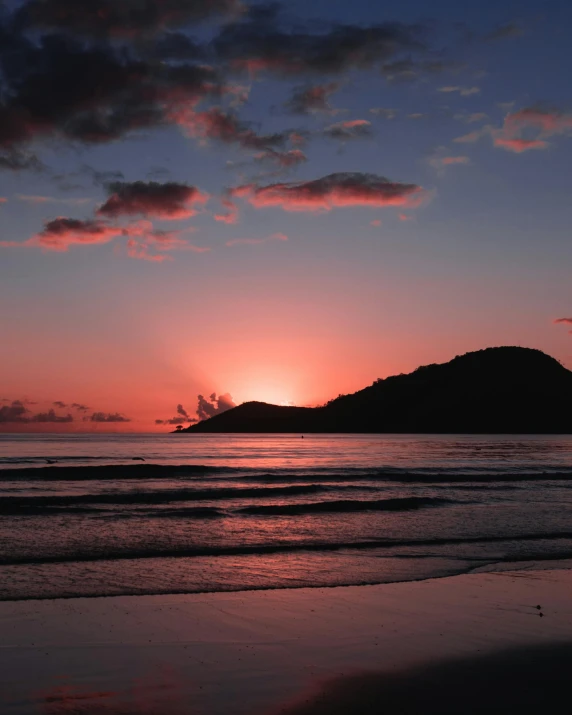 a sunset over a body of water with a mountain in the distance, on beach, profile image