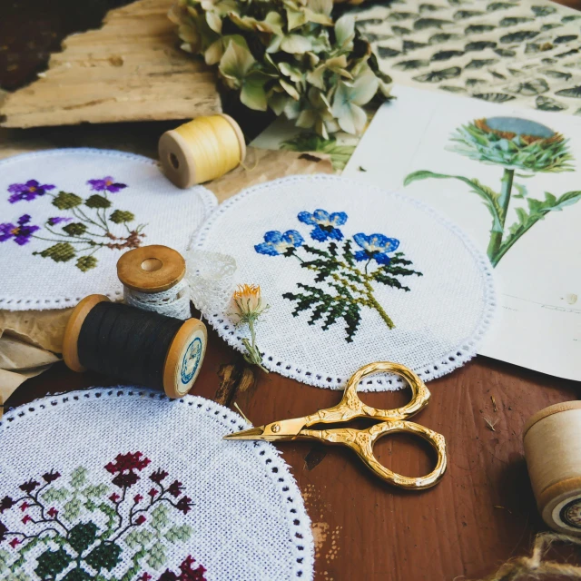 a pair of scissors sitting on top of a table, a cross stitch, by Zofia Stryjenska, pexels contest winner, arts and crafts movement, intricate plants, round format, brown