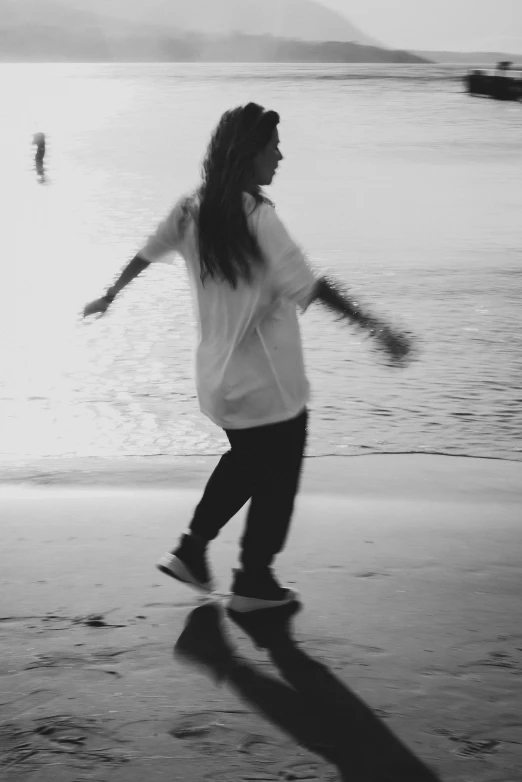 a black and white photo of a woman walking on the beach, happening, dance meditation, billie eilish, low quality, ((oversaturated))