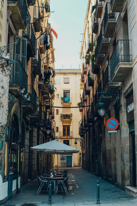 a narrow alley with tables and umbrellas, by Carlo Carrà, pexels contest winner, graffiti, gothic quarter, from the distance, square, old apartment