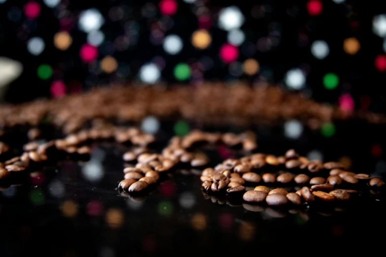 a pile of coffee beans sitting on top of a table, by Julia Pishtar, shot at night with studio lights, neck chains, thumbnail, shaped focus