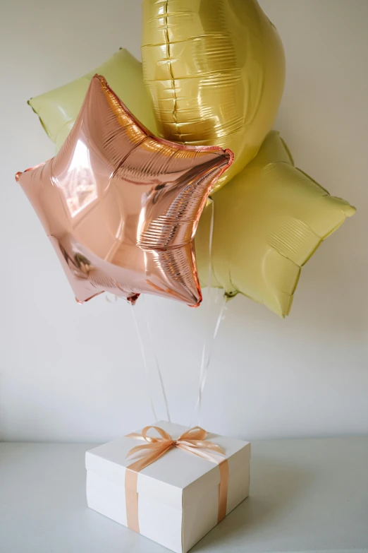 a box with a bunch of balloons attached to it, by Eden Box, rose gold, 3 colours, ivy's, sunburst