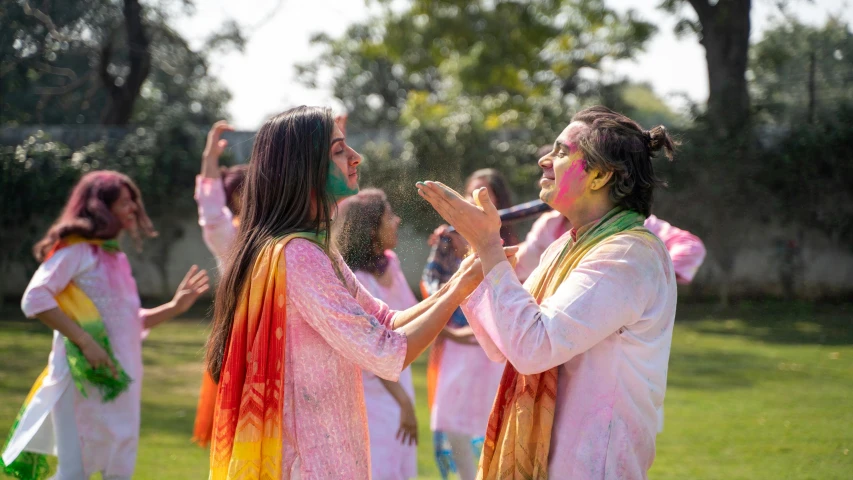 a group of people standing on top of a lush green field, holi festival of rich color, profile image, woman holding another woman, college