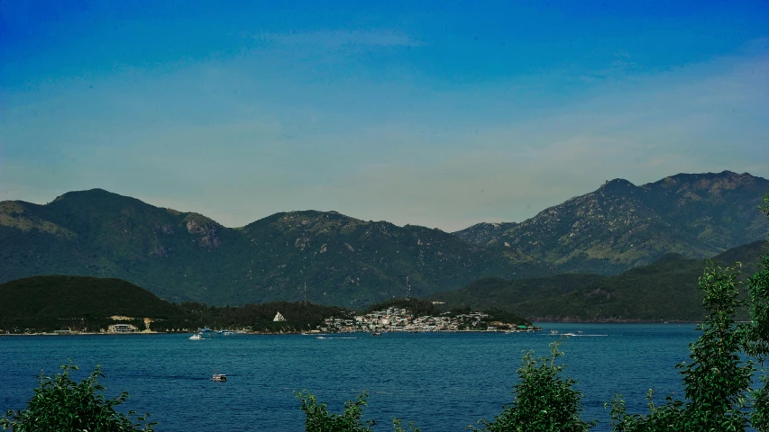 a large body of water with mountains in the background, pexels contest winner, hurufiyya, a still of kowloon, picton blue, subtitles, listing image