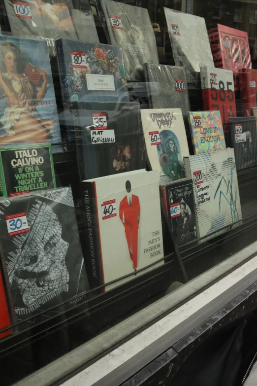 a window that has a bunch of books in it, an album cover, dada, ((in a super market costco)), displays, display”