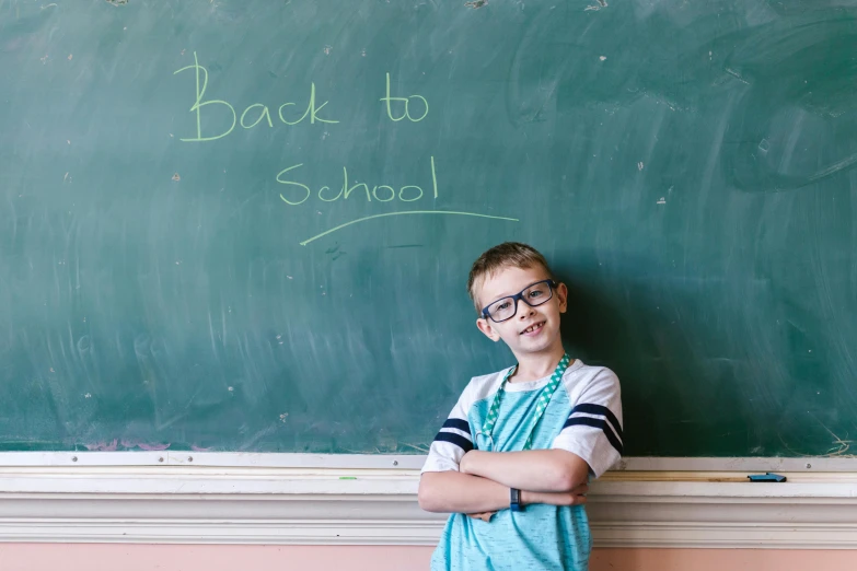 a young boy standing in front of a blackboard, by Carey Morris, pexels, a still of a happy, back to back, school, background image