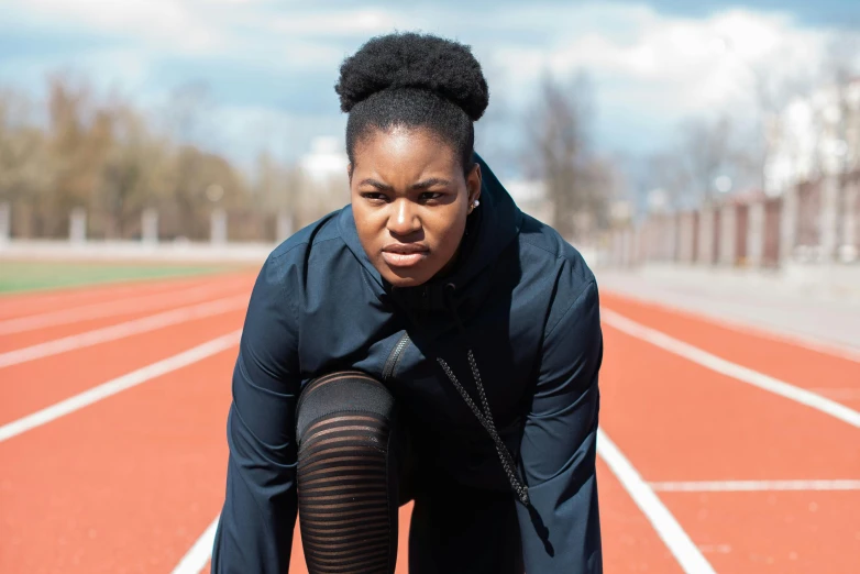 a woman squatting on a running track, by Barthélemy Menn, pexels contest winner, concerned expression, full figured, black tendrils, promotional image