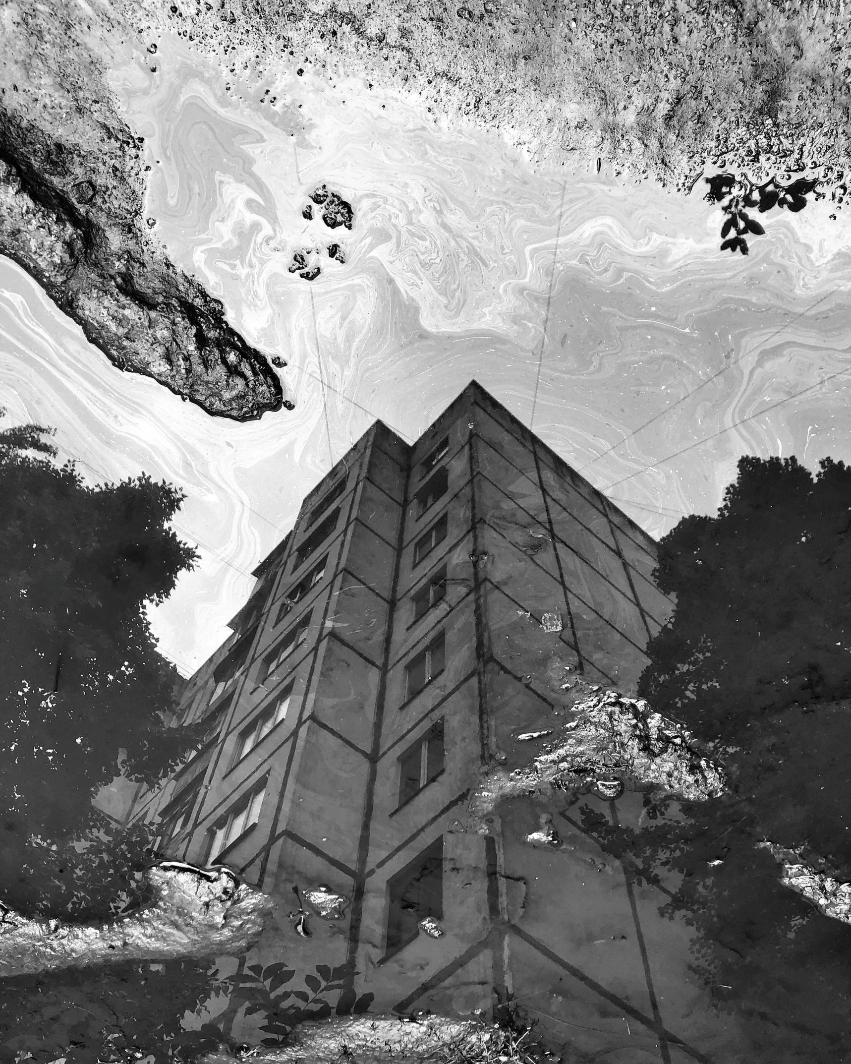 a black and white photo of a tall building, an album cover, inspired by Piranesi, wet puddles reflecting, marbled, soviet apartment building, lsd trip