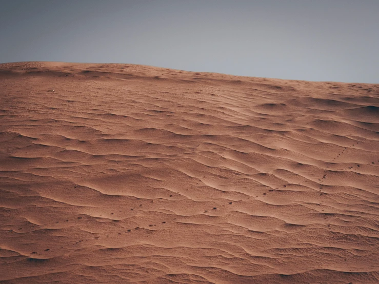 a person riding a snowboard on top of a sandy hill, an album cover, pexels contest winner, hurufiyya, red dusty soil, very dull muted colors, martian, texture of sand