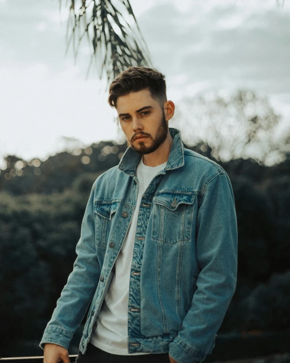 a man with a beard wearing a denim jacket, non binary model, liam, scenic view, album photo