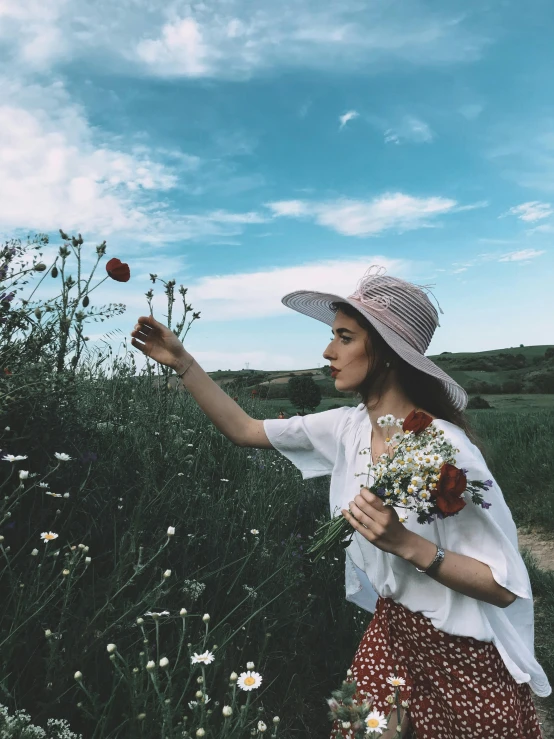 a woman standing in a field holding a bunch of flowers, pexels contest winner, 🎀 🧟 🍓 🧚, she is wearing a hat, tumblr aesthetic, instagram post