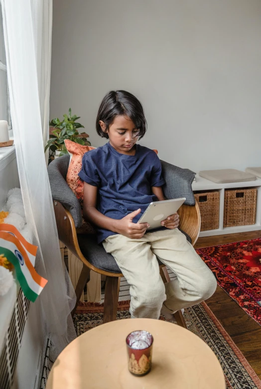 a little girl sitting in a chair reading a book, indian flag, mobile learning app prototype, bay area, teen boy