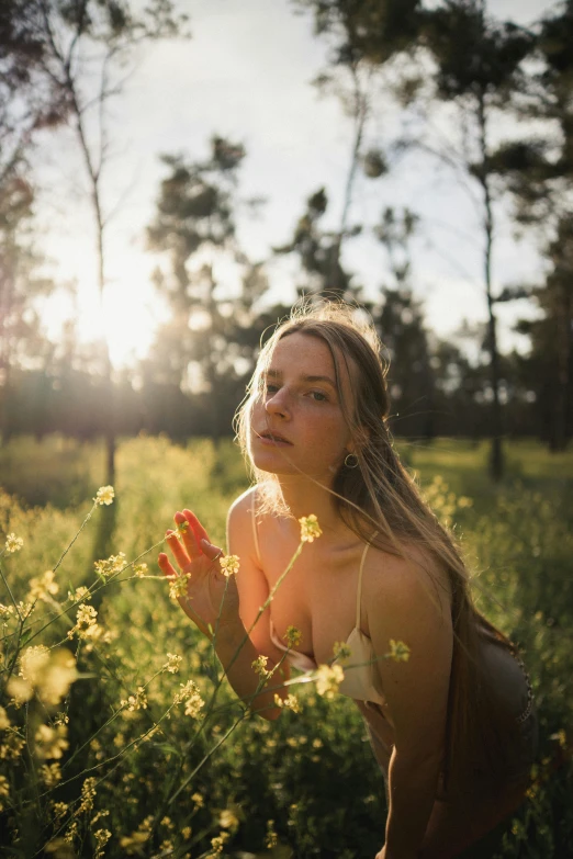 a woman standing in a field of yellow flowers, inspired by Elsa Bleda, unsplash contest winner, sunlight filtering through skin, sitting on green grass, soft pale golden skin, (golden hour)