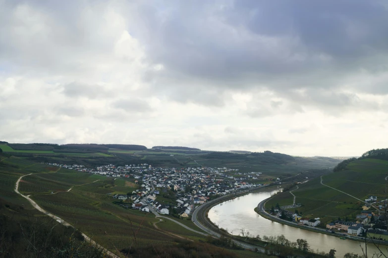 a river running through a lush green hillside, an album cover, by Matthias Stom, pexels contest winner, happening, city panorama, overcast, wine, small town surrounding